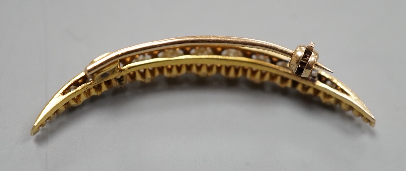 An early 20th century yellow metal and graduated cultured pearl set crescent brooch, 40mm, gross weight 3.7 grams.
